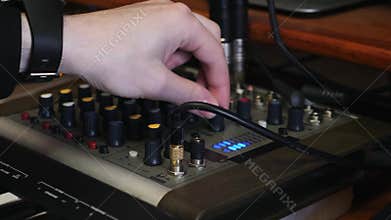Hand turning knobs and pushing buttons on music sound mixing board at home recording studio. close up view of hands mixing and mas