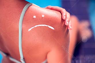 Woman with sun protection cream on her burned skin in the shape of sad smile. Summer, healthcare and vacation concept