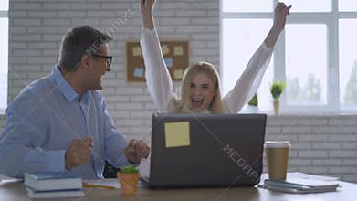 Happy businessman feeling excited looking at laptop screen sitting at workplace, celebrates business success, online win