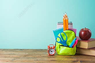 Back to school background with small backpack, books and apple on wooden table