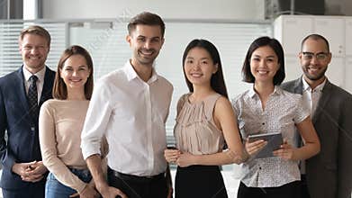Happy diverse professional leaders looking at camera stand with employees