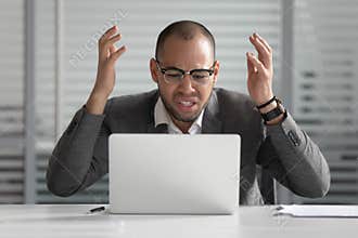 Angry african business man using laptop mad about computer problem