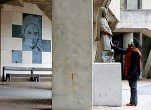 Black woman prays near statue of Saint Bernadette in Lourdes