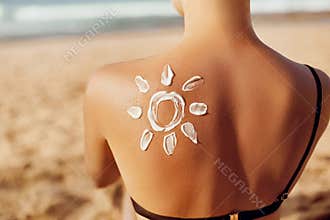 Skin care. Sun protection. Woman apply sun cream. Woman With Suntan Lotion On Beach In Form Of The Sun.