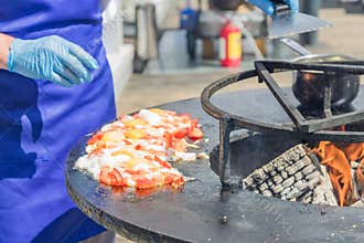 Chef cooks fried eggs with tomatoes at the festival. Street food prepared on grill