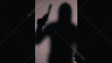 Silhouette of bandit with gun aiming through closed doors glass, contract murder