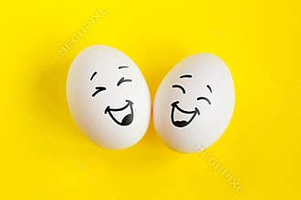 Two white eggs on yellow background concept. Emotions laughter and happiness.