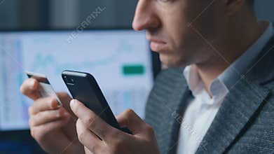 Close up portrait business man shopping online with credit card using smartphone at office. Online banking mobile app.