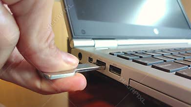 Hand connecting USB flash drive to laptop computer