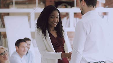 Smiling black female employee get rewarded handshake caucasian boss