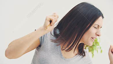 Smiling young woman is showing keys to her new flat, dancing and waving her hands joyfully.