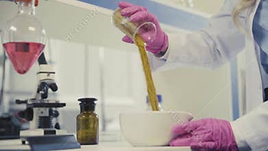 Scientist pours golden powder into bowl on table closeup