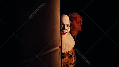 Creepy clown with crazy smile on his face suddenly appears around the corner