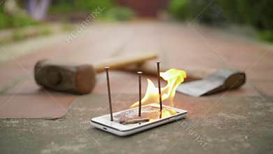 Broken with nails mobile phone on ground is on fire in slow motion