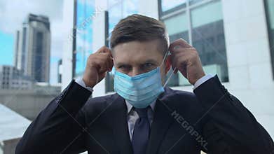 Serious man in suit putting on protective mask, seasonal flu epidemic in country