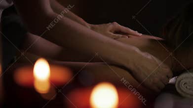Close up of young girl having hand massage in spa salon, The procedure in a massage parlor by the light of candles.