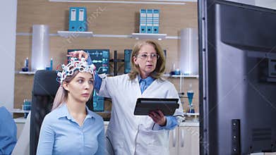 Dolly shot of female doctor checking brain activity of her female patient