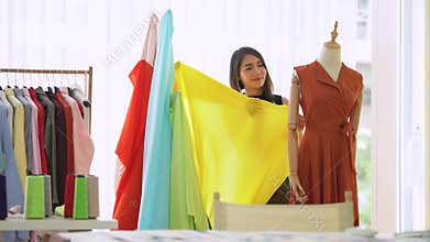 Young designer measuring and matching clothe materials for new collection in design studio