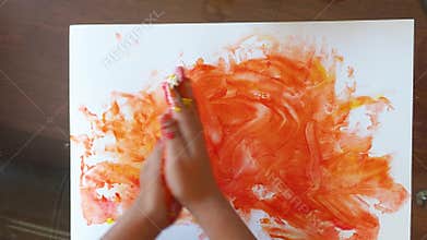 Baby child is painting with hands using colored finger gel paints, heart shape