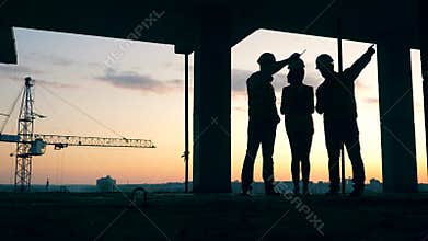 Workers stand on a building site, talking. Construction workers at modern construction site.