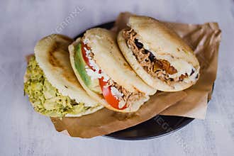 Arepa, typical food from Venezula and Colombia, on a white background ready to eat. Arepas are filled with desmechada meat, avocad