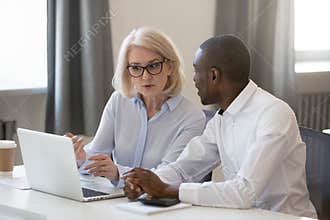 Serious busy aged mentor helping to new african employee
