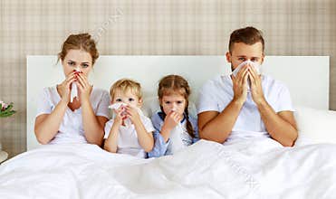 Colds and viral diseases. family with runny nose and fever in bed