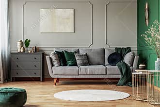 Stylish emerald green and grey living room interior design with abstract painting on the wall