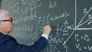 Portrait of elderly man college teacher underlining formula on chalkboard writing