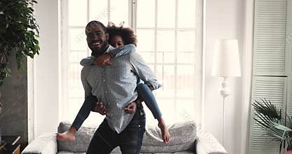 African dad carrying kid daughter giving piggyback ride at home