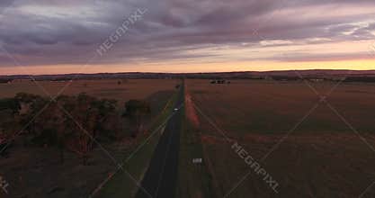 Car Driving Down Road With Sunset