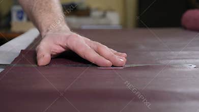 Manually cutting leather during craft manufacturing goods. Workshop of skinner, close-up shot showing hands of master