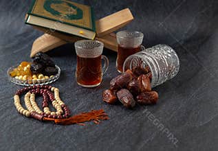 Food Ramadan Sweets mixed of dried fruits and nuts Glass Tea with  rosary and the Quran on the table,  Concept: month fasting cult