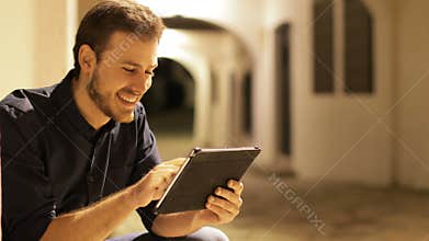 Man browsing tablet content in the night