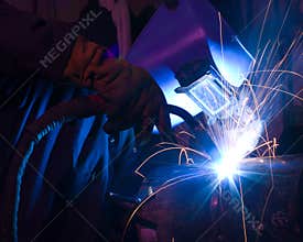 Dramatic blue-lit MIG welding close