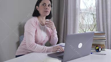 Nervous Caucasian young woman looking at screen, hearing something, closing laptop and leaving. Brunette wife or mother