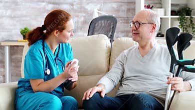 In retirement home nurse is talking with elderly man about drugs dosage