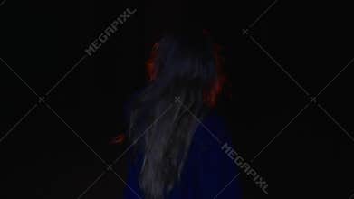 Back view of girl holding oil lamp and walking in dark forest at night