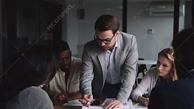 Young businessman sharing company development ideas with diverse partners.