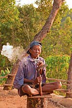 A local elderly worker smoking cigarette on chopped tree trunk at Punthuk Setumbu Hills