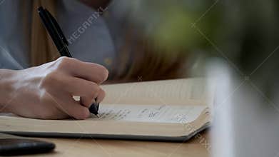 A woman's hand writing in her agenda in the office.