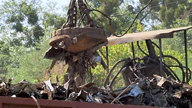 4k footage of big industrial magnet on the junkyard lifting iron and loading it in metal container. Concept of metal