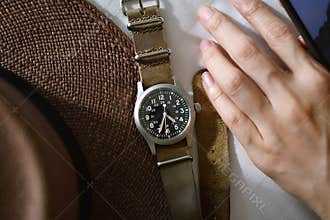 Vintage military wristwatch with nato leather strap and brown straw hat.