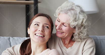 Cheerful two age generations women bonding on sofa, closeup portrait