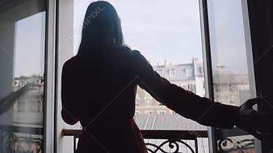 Silhouette shot of happy young local woman walking up to balcony window, enjoying sunny Eiffel Tower view slow motion.