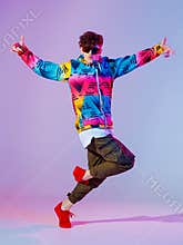 Boy dancing in neon light studio. Acrobatic dancer. Stylish flex.