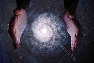 Creationism concept. Hands of God are creating Galaxy in universe.