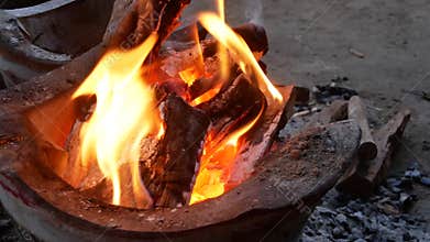 Hot burning charcoals on a stove placed on the ground, ready for cooking