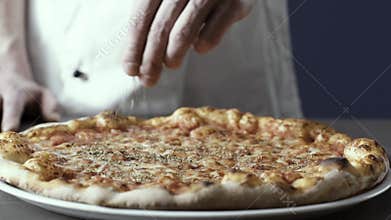 Professional cook finishing pizza with oregano