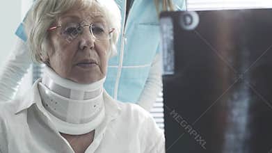 Doctor examining an injured senior woman with cervical collar